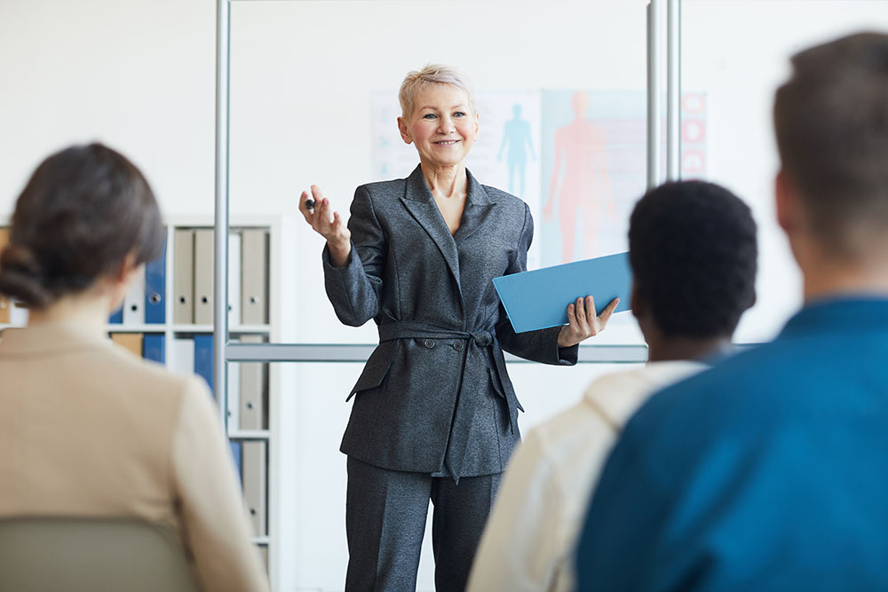 Portrait of smiling female business coach giving speech to audience during seminar, copy space